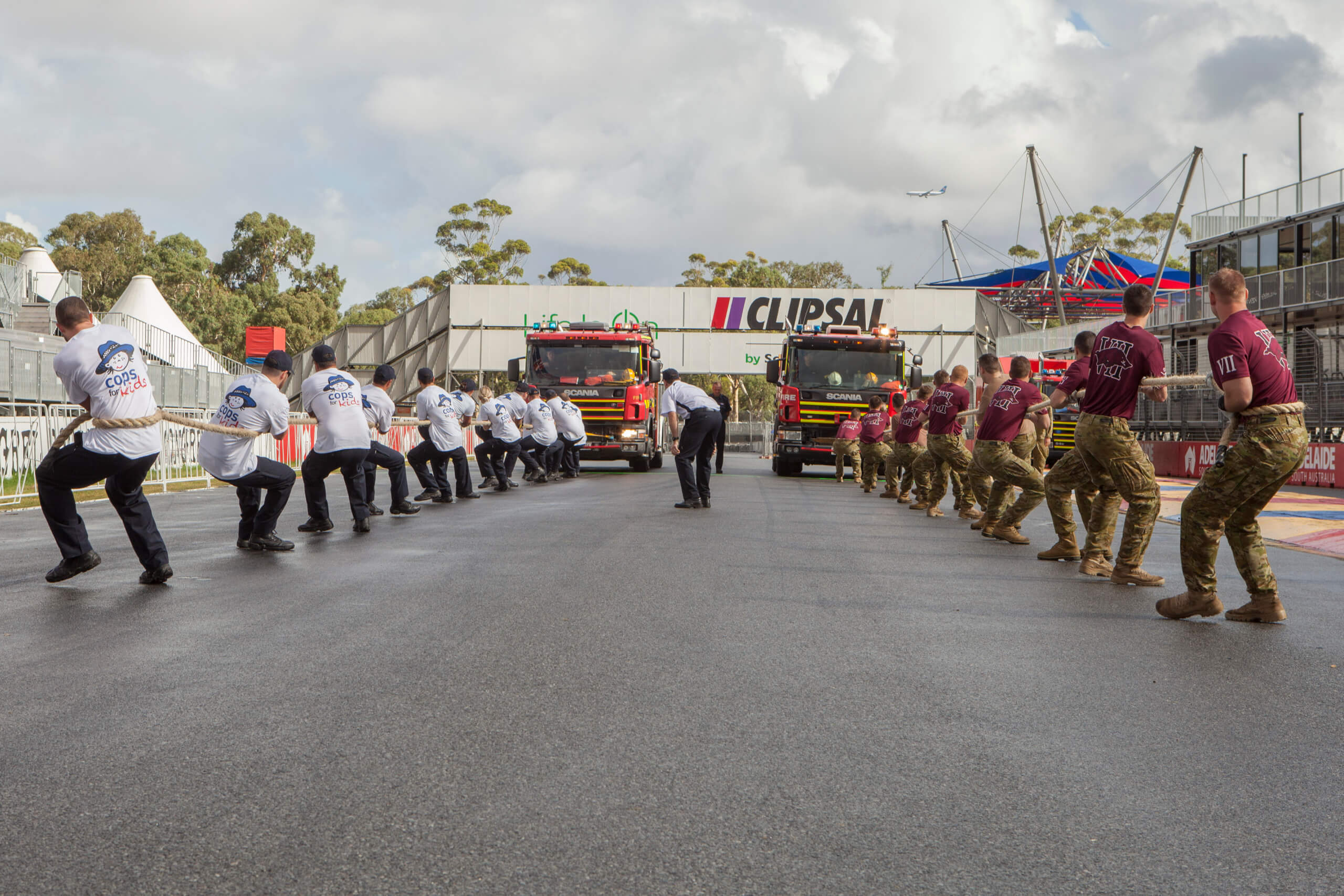 The South Australian Police "Cops for Kids" team (left) races against the Australian Army 7th Battalion, Royal Australian Regiment team in a competition to pull a fully loaded fire truck 75 metres first across the Clipsal 500 race track finish line, to help raise charity funds for the Team Kids Easter Appeal 2017 Fire Engine Pull. *** Local Caption *** The TeamKids Easter Appeal is a perfect example of what TeamKids is all about – people coming together to make a positive difference within our community. The funds raised, through donations, sponsorship, gifts, pledges and in kind support, will help continue to fund important equipment, research and services vital for over a quarter of a million children, babies and women who rely on the Women’s and Children’s Hospital each year.