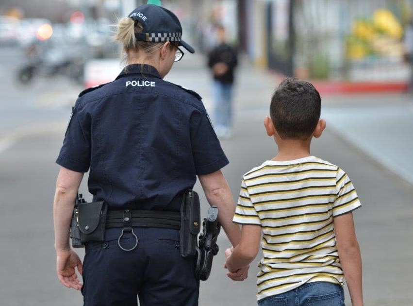 Police officer walking holding child's hand